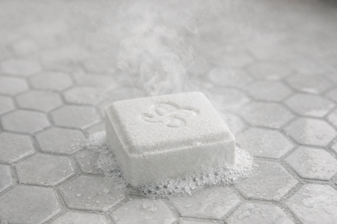 Silknsoak single-use concentrated shower steamer tablet placed on shower floor, releasing steam-activated aroma in a modern shower.